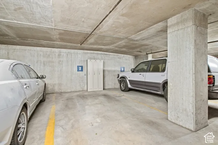 Covered garage featuring concrete structural elements and integrated metal storage lockers