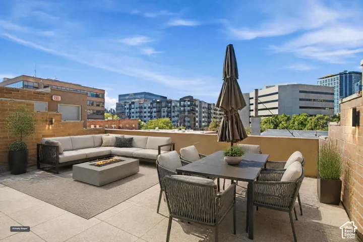 Rooftop terrace featuring concrete paver flooring, stone masonry walls, and integrated exterior sconce lighting