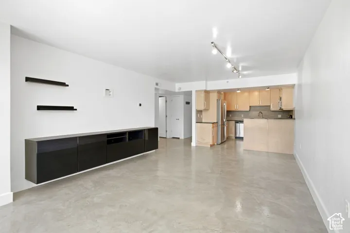 Polished concrete flooring, built-in black cabinetry, floating shelving, light wood-finish cabinetry, and stainless steel appliances