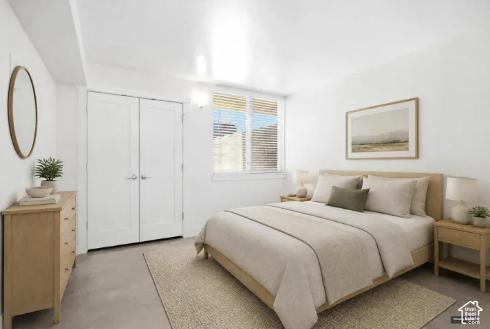 Neutral-toned room featuring a smooth concrete floor, double-door closet, and window with horizontal blinds