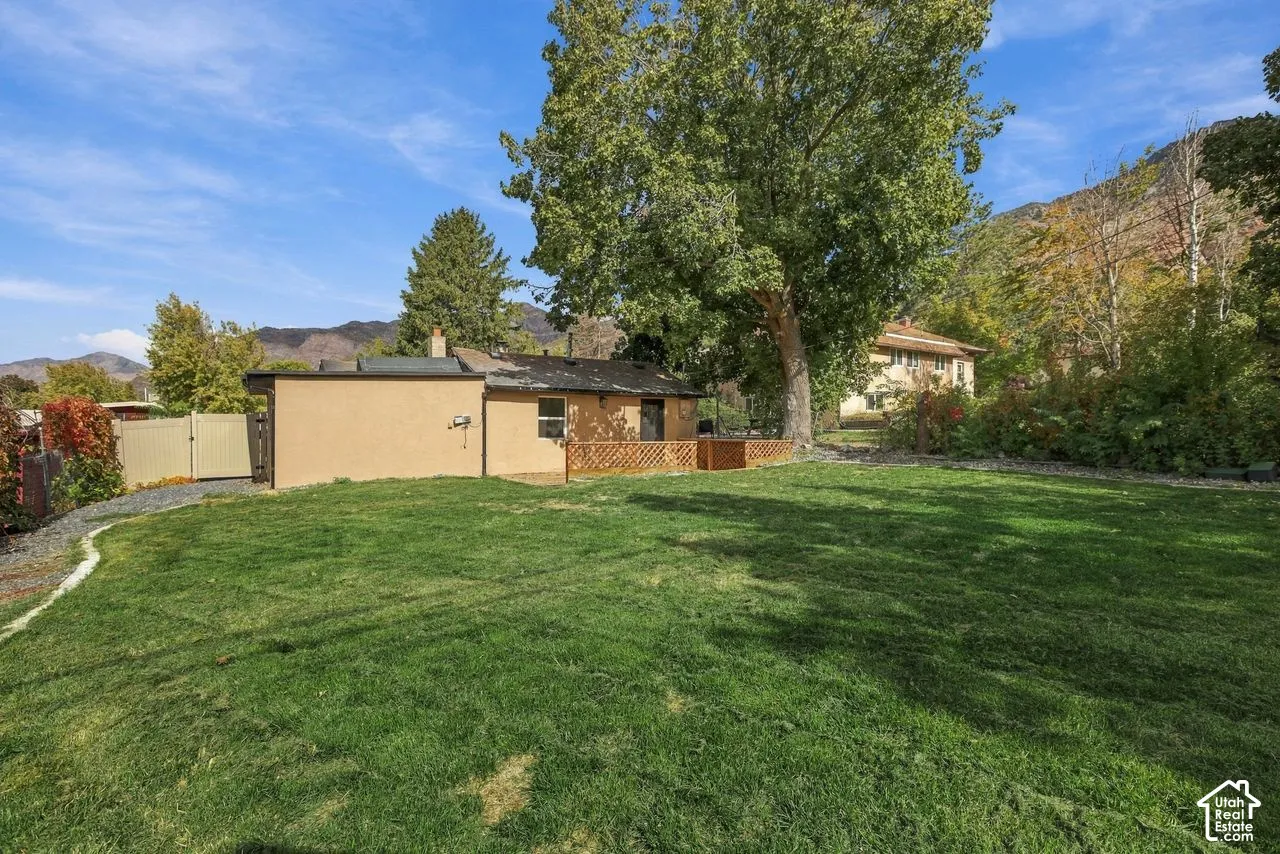Expansive backyard featuring a level lawn, mature trees, mountain backdrop, and privacy fencing