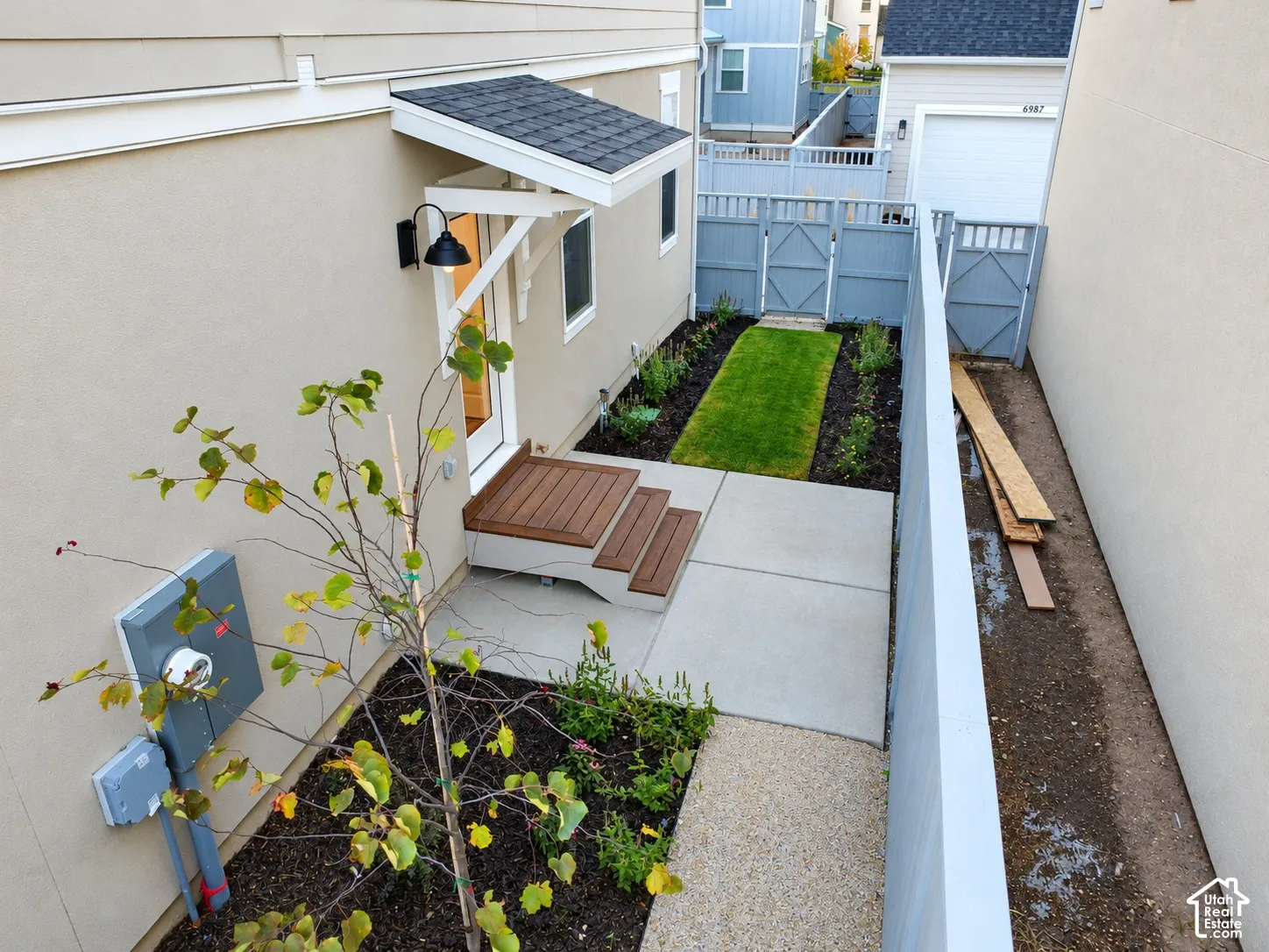 Exterior side yard featuring a concrete patio, wood-finish stairs, a covered entryway, and enclosed privacy fencing