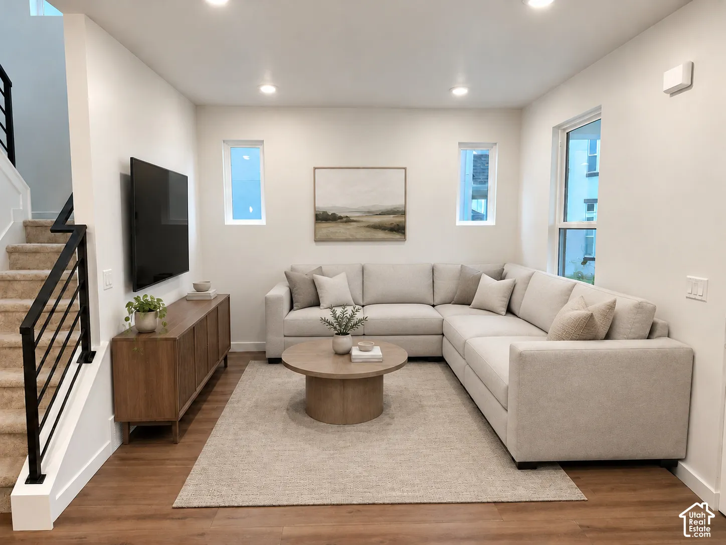 Interior space featuring recessed lighting, wood-finish flooring, dual vertical accent windows, and a staircase with a matte black metal railing