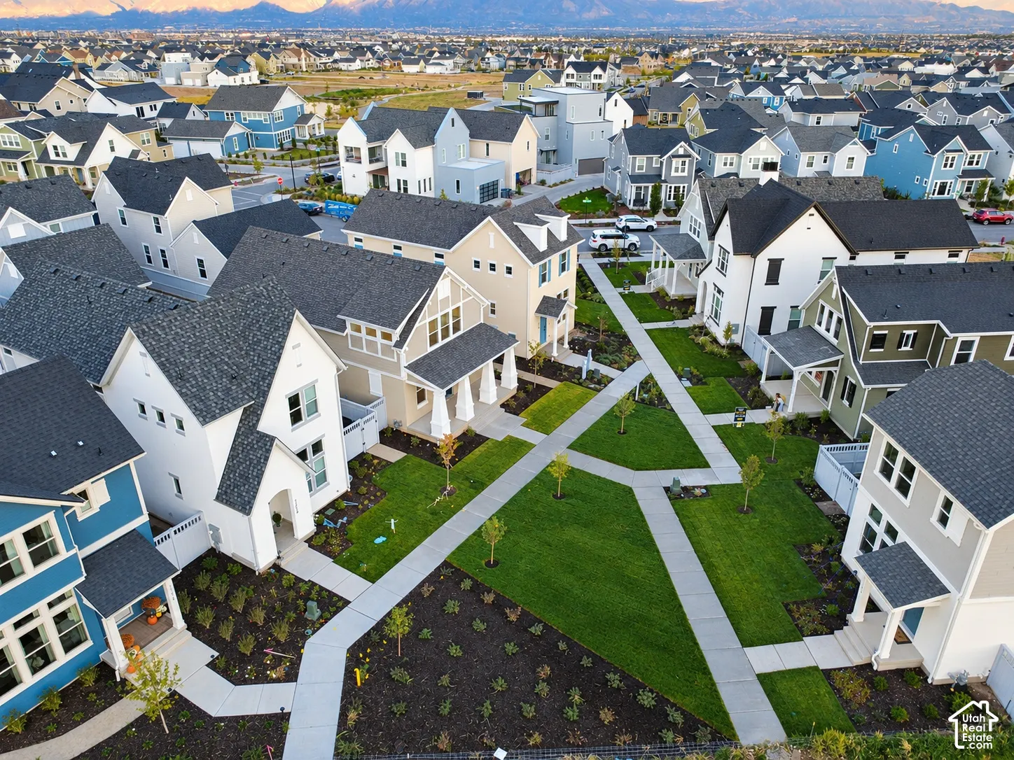 Aerial perspective of residential exteriors featuring multi-story architectural designs, pitched roofs, concrete walkways, and manicured green spaces
