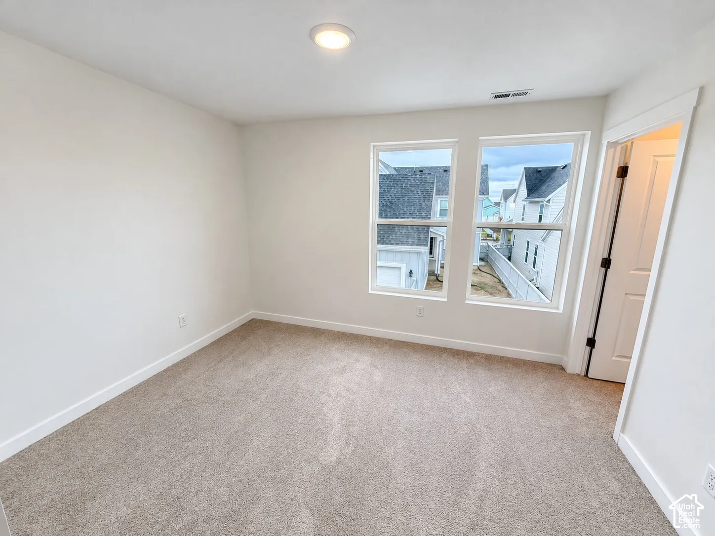 Neutral interior featuring wall-to-wall carpeting, dual windows, and a recessed ceiling light
