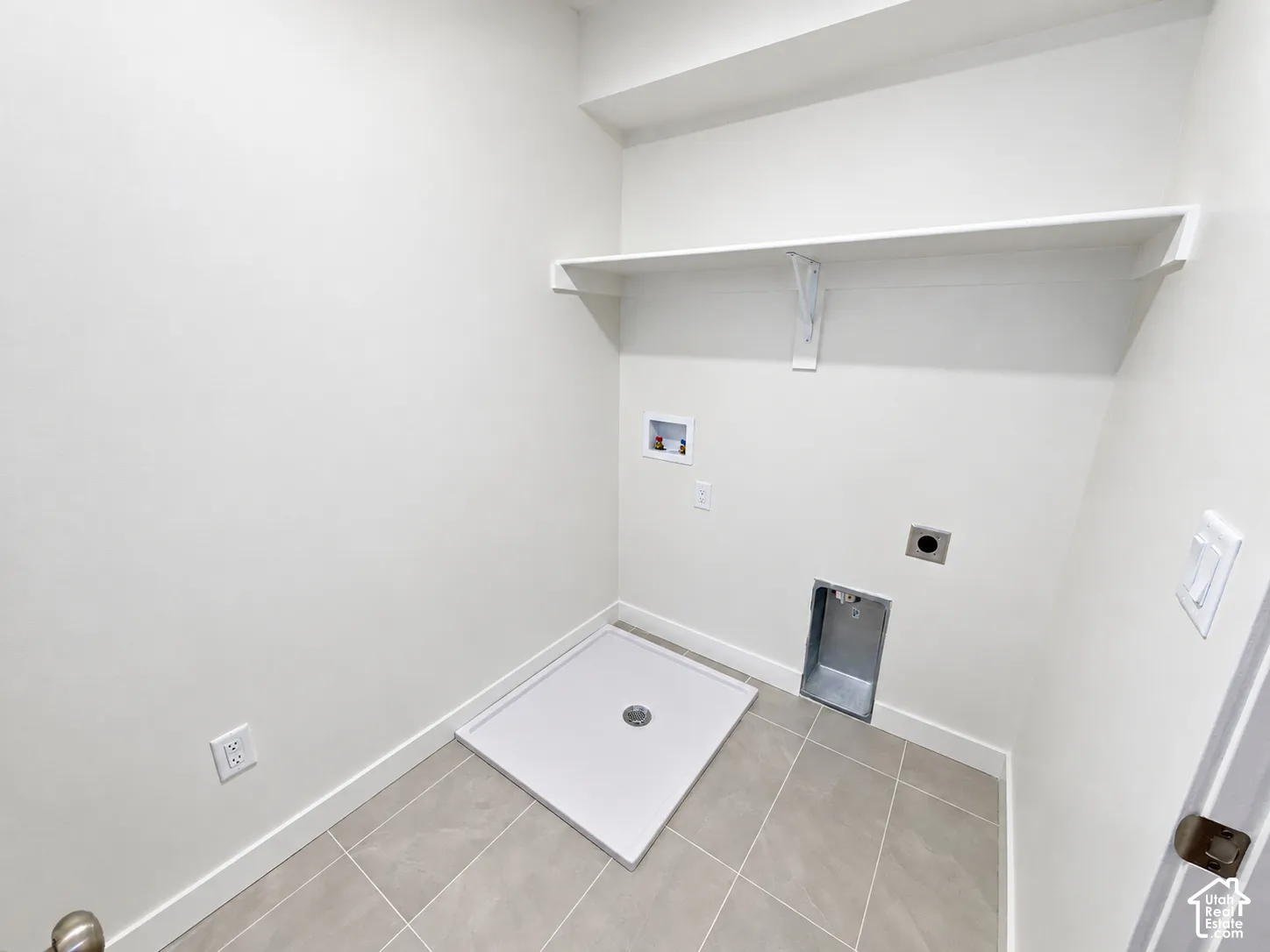 Laundry area featuring tile flooring, a white built-in shelf, and recessed utility connections