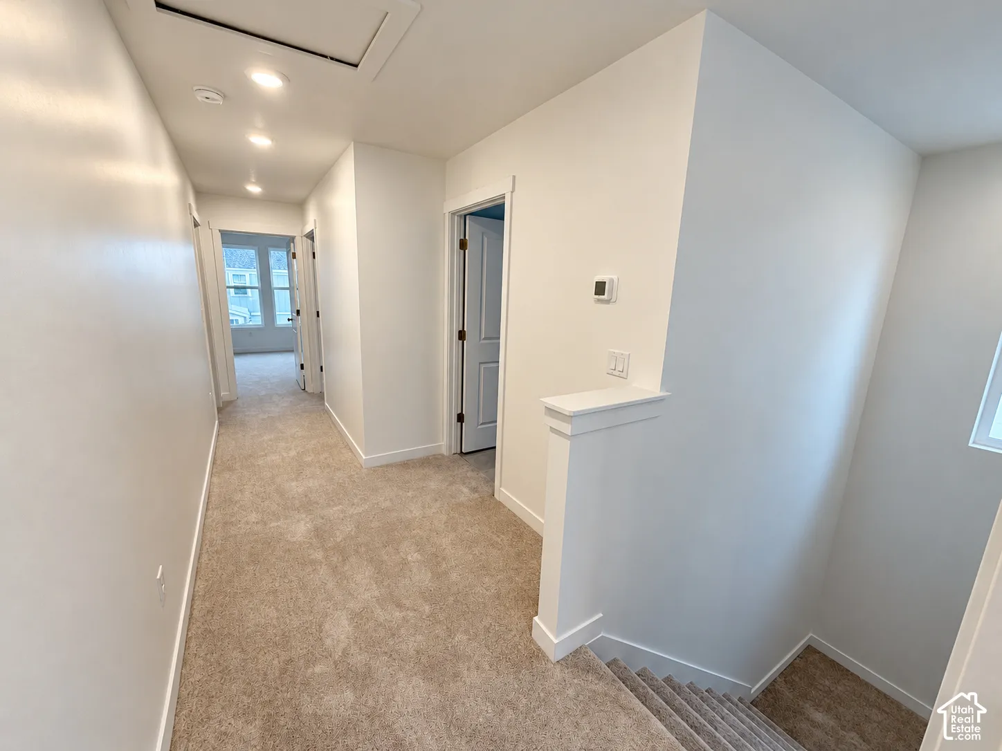 Hallway featuring neutral wall-to-wall carpeting, recessed ceiling lighting, and crisp white interior paint