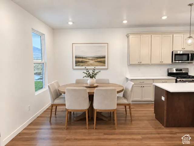 Kitchen featuring shaker-style cabinetry, a contrasting central island with a white countertop, recessed lighting, and wood-finish flooring