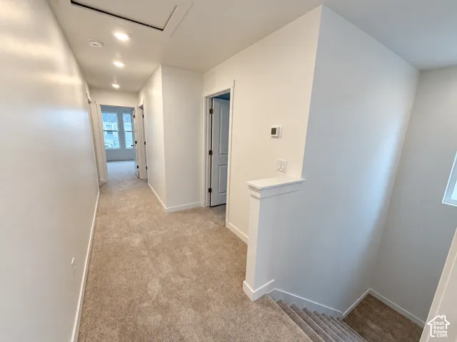 Hallway featuring neutral wall-to-wall carpeting, recessed ceiling lighting, and crisp white interior paint