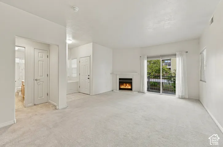 Living space featuring wall-to-wall carpeting, a fireplace with a white mantel, and sliding glass doors with access to a private balcony