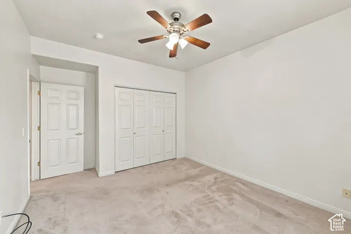 Bedroom featuring wall-to-wall carpeting, a multi-panel closet with dual doors, and a ceiling fan with integrated lighting