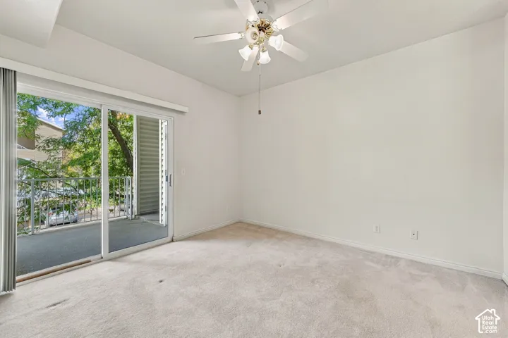 Primary Bedroom with neutral-toned wall-to-wall carpeting, ceiling-mounted light fixture with a multi-blade fan, and glass sliding door providing access to a private balcony