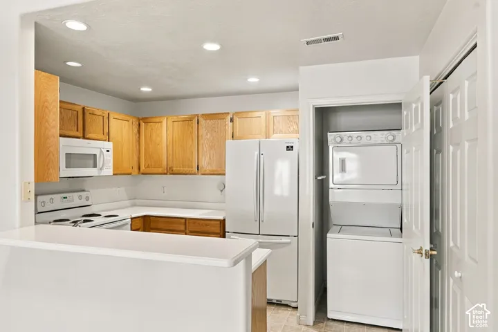 Kitchen featuring natural wood cabinetry, white appliances, a counter, and recessed lighting, with an enclosed laundry area