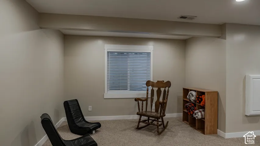 Neutral-toned interior space featuring light-colored wall paint, plush carpeting, recessed lighting, and a window with horizontal blinds