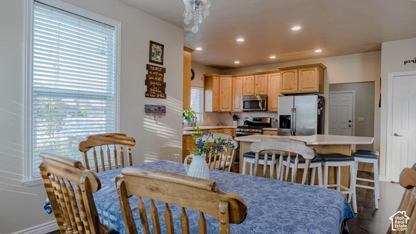Kitchen featuring natural wood cabinetry, quartz countertops, a central island with bar seating, stainless steel appliances, and recessed lighting