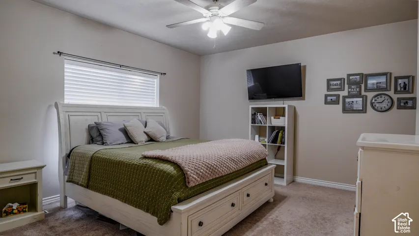 Bedroom featuring neutral wall paint, carpeted flooring, and a ceiling fan with integrated light fixture
