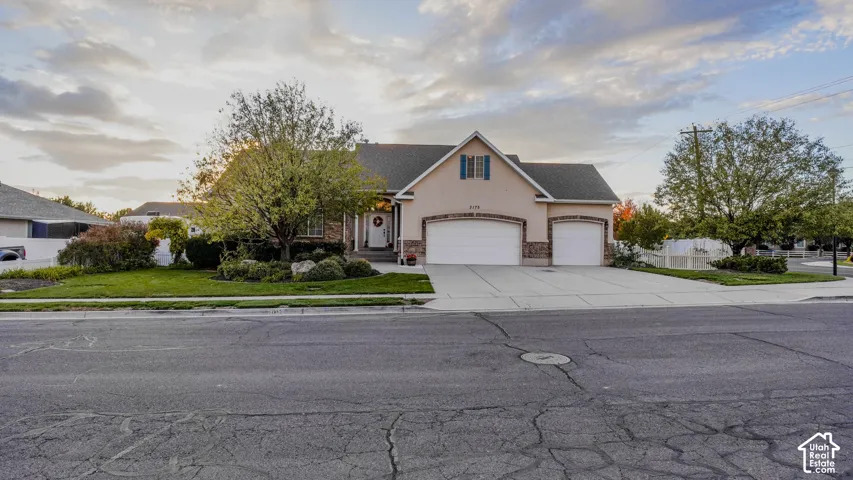 Exterior facade featuring stucco siding, stone veneer accents, an attached three-car garage, and a concrete driveway