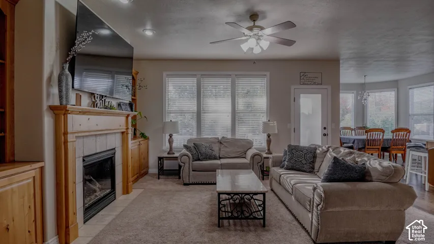 Gas fireplace featuring a wood mantel and tile surround, custom built-in cabinetry, ceiling fan with integrated lighting, and expansive windows