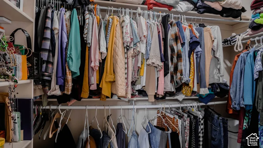 Walk-in closet featuring floor-to-ceiling built-in shelving and dual-tier hanging rods