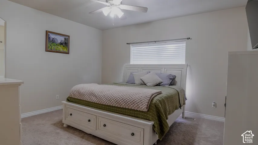 Neutral-toned interior featuring wall-to-wall carpeting, a ceiling fan with integrated lighting, and a window with horizontal blinds