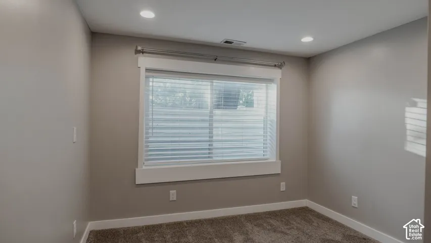 Neutral-toned interior featuring recessed lighting, a single sliding window with custom millwork framing, and carpeted flooring
