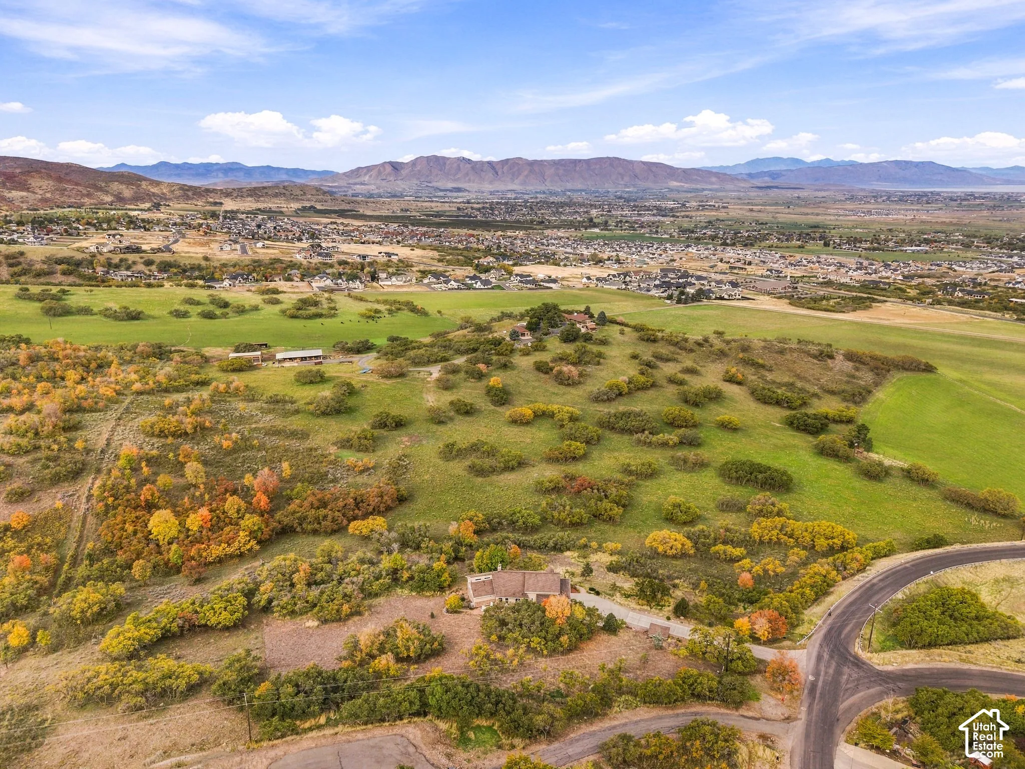 Aerial perspective of a sprawling property featuring mountainous terrain, rolling topography, mature trees, and paved road access
