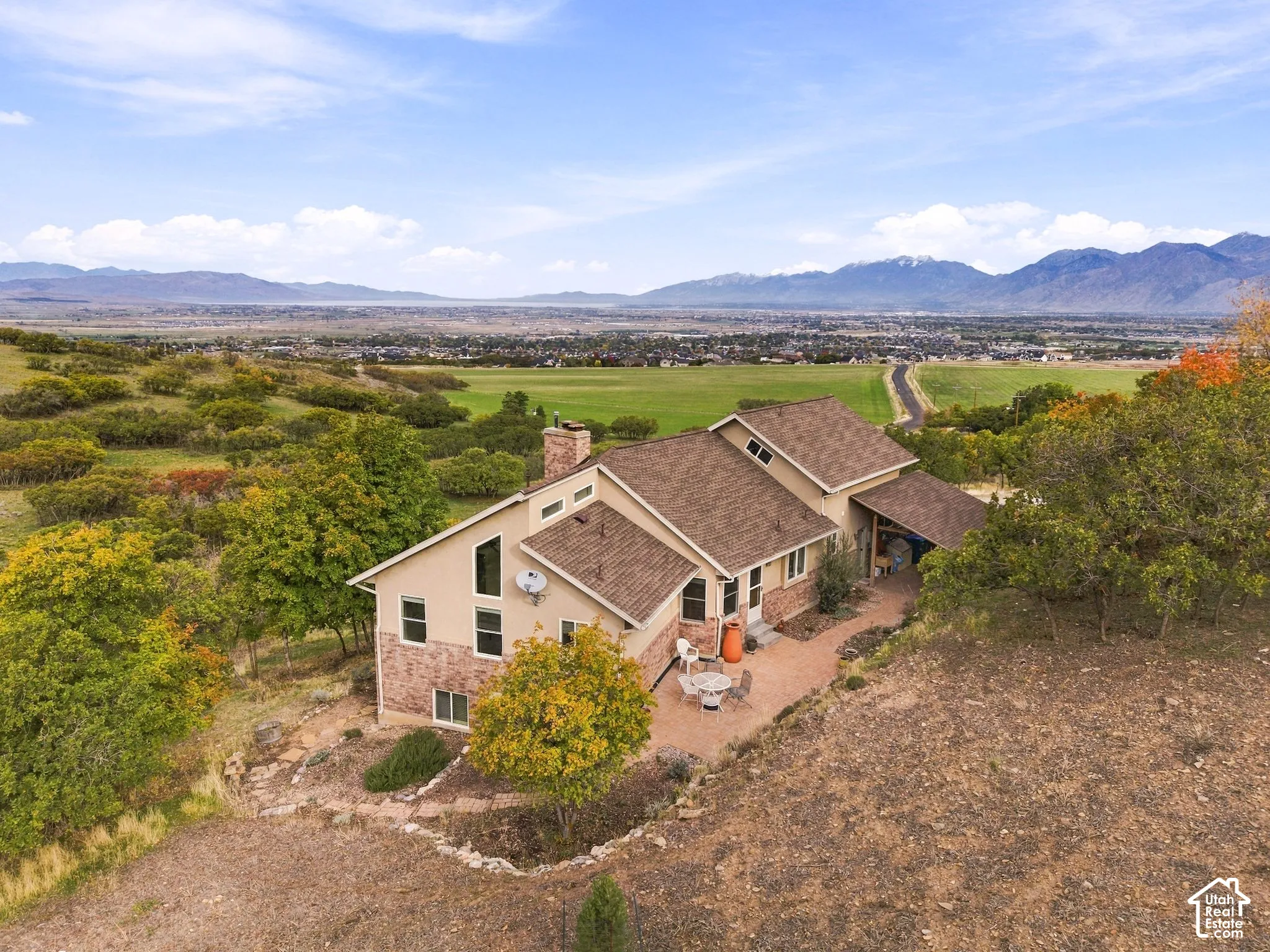 Multi-level exterior featuring a brick and stucco facade, a shingle roof, mountain and valley scenery, and a stone-paver patio