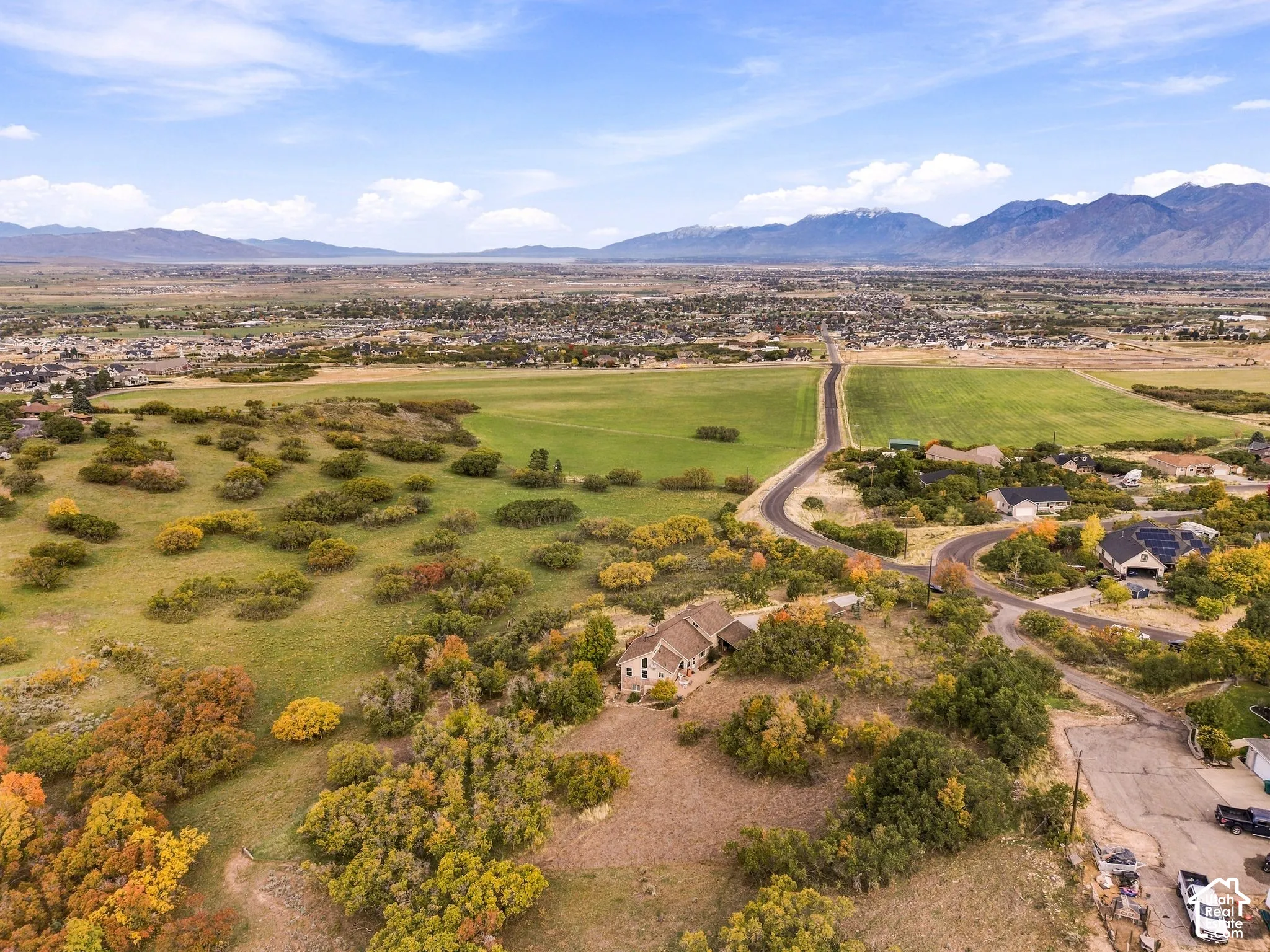 Aerial perspective of property featuring extensive acreage, mature native trees, and panoramic mountain backdrop