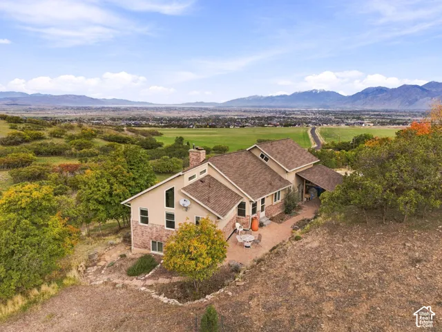 Multi-level exterior featuring a brick and stucco facade, a shingle roof, mountain and valley scenery, and a stone-paver patio