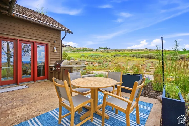 Stamped concrete patio featuring a built-in outdoor grill station, lap siding exterior, and multi-panel red-trimmed glass doors