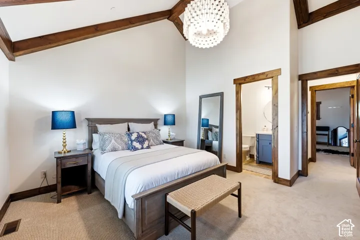 Vaulted ceiling with exposed wood beams, beaded chandelier, and wood-trimmed door casings