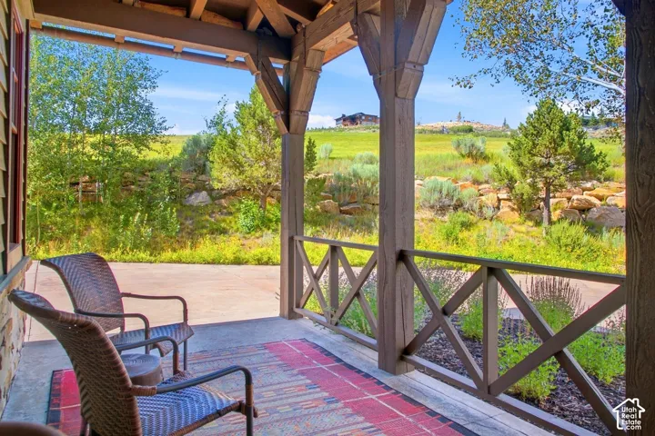 Covered patio featuring heavy timber support posts, decorative cross-buck railing, and concrete flooring
