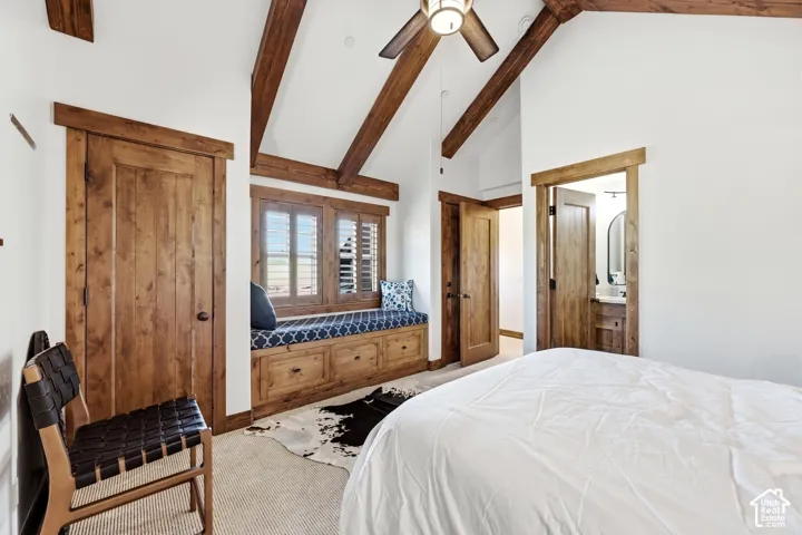 Vaulted ceilings with exposed wood beams, built-in wooden window seat with integrated storage, wood-trim door casings, and wooden doors
