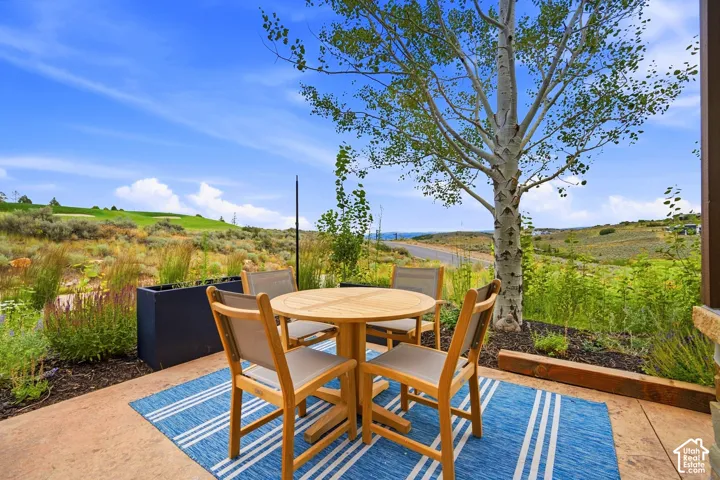 Concrete patio featuring native landscaping, mature tree, and open terrain surroundings