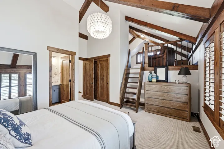 Vaulted ceilings featuring exposed wooden beams, natural wood interior trim, wood staircase, balcony railing, and decorative pendant lighting