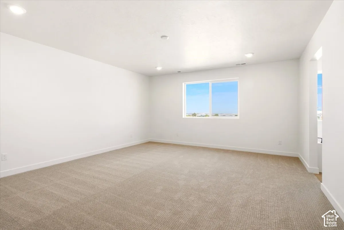 Interior room featuring neutral wall-to-wall carpeting, recessed ceiling lighting, and a single-pane sliding window