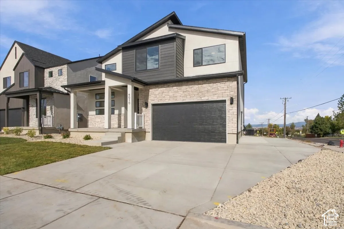 Multi-story exterior featuring a stone veneer facade, vertical siding, an attached two-car garage, and a covered front porch