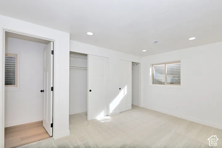 Neutral-toned carpet, recessed lighting, dual sliding-door closets, and inset windows