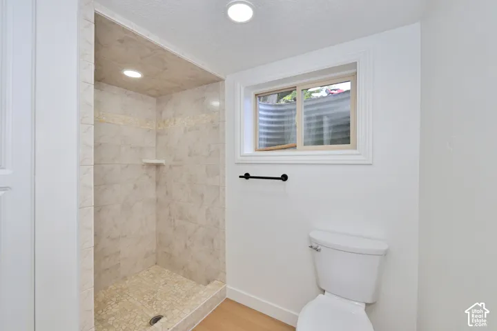 Walk-in shower with tiled surround and built-in shelving, matte black hardware, recessed ceiling lighting, and sliding window with egress well
