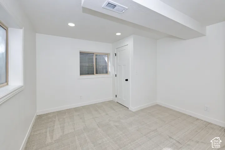 Neutral-toned wall-to-wall carpeting, recessed LED lighting, and a solid-core single-panel door with matte black hardware