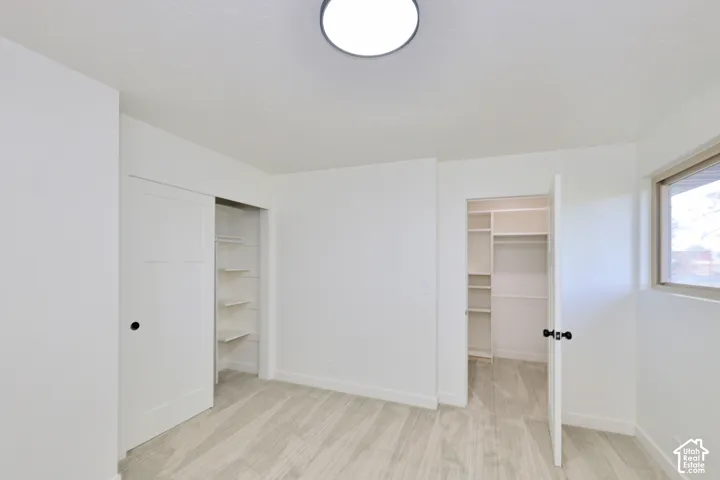 Interior space featuring wood-finish flooring, a flush-mount light fixture, a sliding panel door, and built-in closet shelving