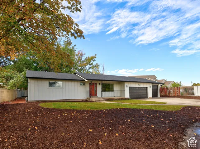 Single-story exterior featuring board and batten siding, a dark shingle roof, a two-car garage, and landscaped ground cover