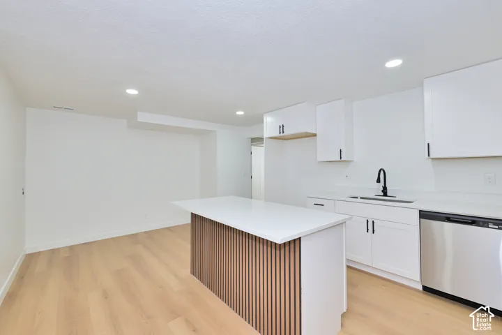 Kitchen featuring white shaker-style cabinetry, quartz countertops, a center island with wood-slat detailing, recessed lighting, and wood-finish flooring
