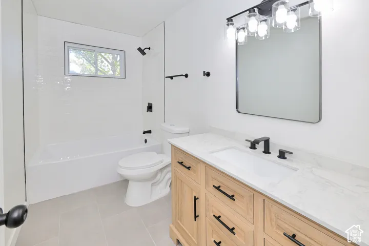 Bathroom featuring a light wood vanity with a white stone-composite countertop, subway tile shower surround, matte black hardware, and an integrated rectangular basin