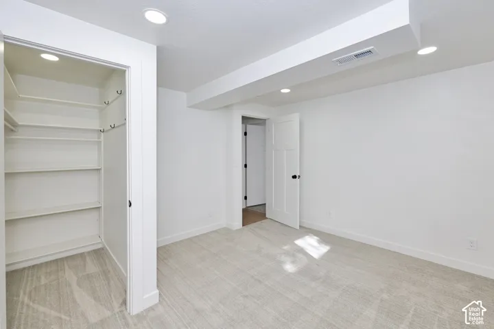 Neutral-toned carpeting, built-in closet shelving, recessed lighting, and a white shaker-style interior door