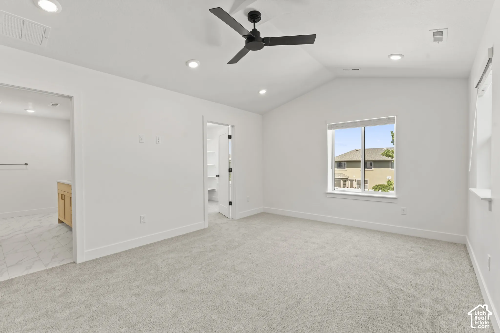 Vaulted ceiling featuring a matte black finish ceiling fan and recessed lighting, neutral carpeting, and large window with exterior exposure