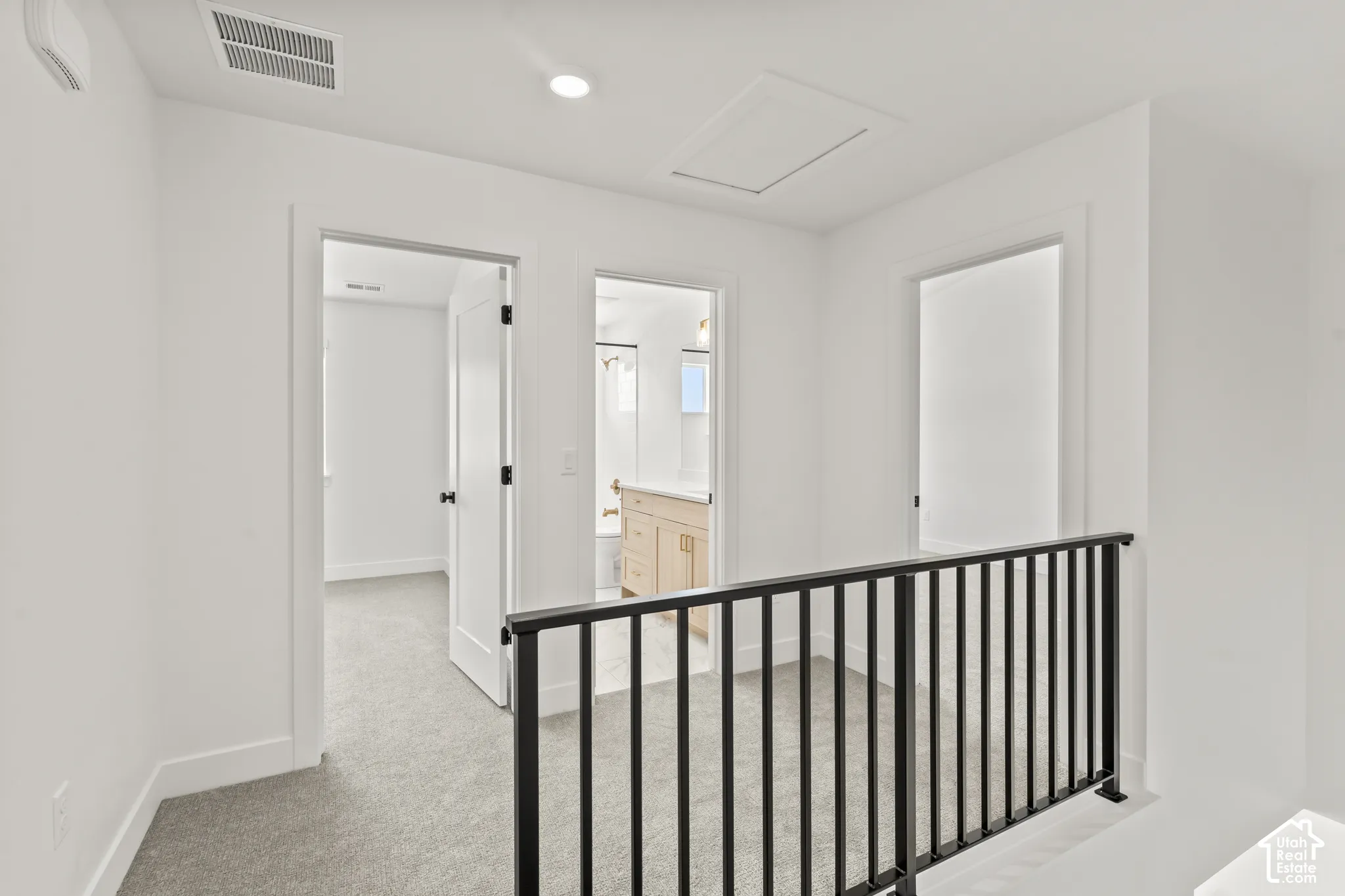 Neutral carpeting, black metal balusters, and solid-core interior doors with matte black hardware