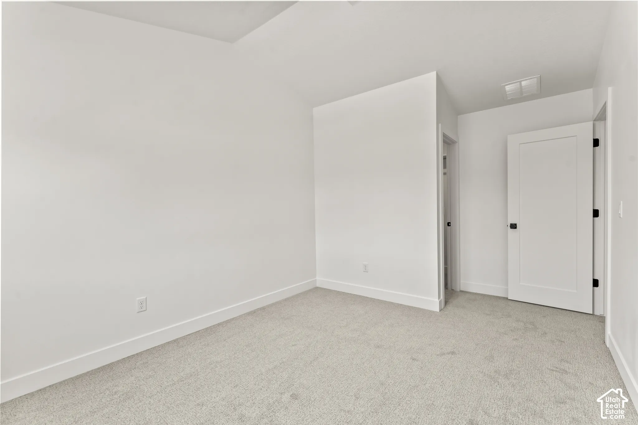 Neutral wall color, vaulted ceiling, and interior door with matte black hardware