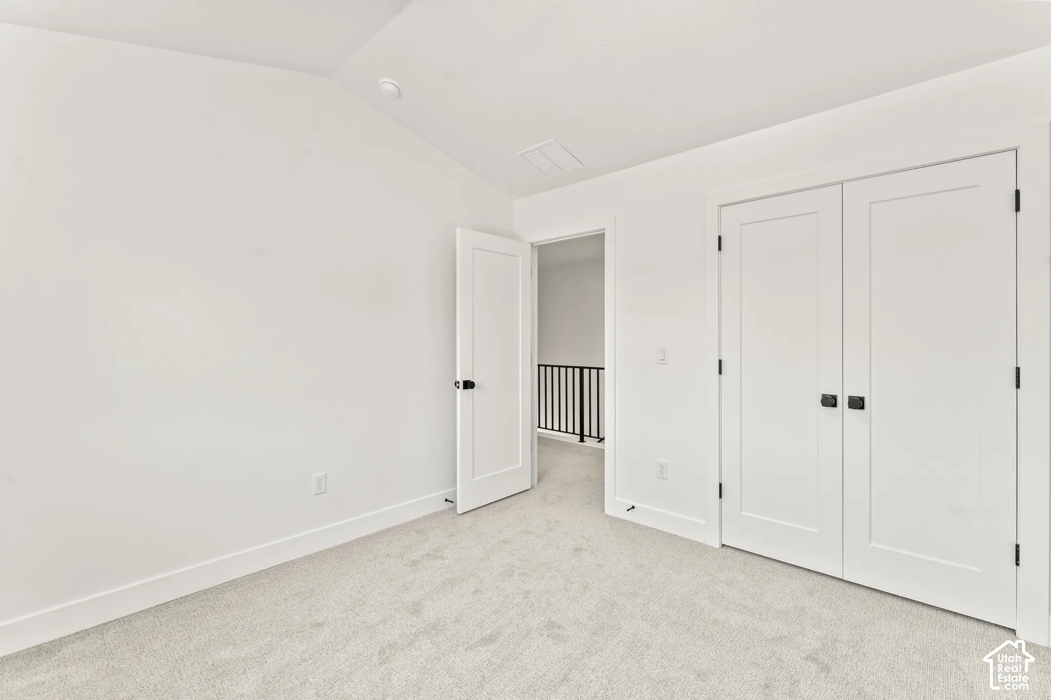Vaulted ceilings, neutral carpeting, and shaker-style interior doors featuring matte black hardware