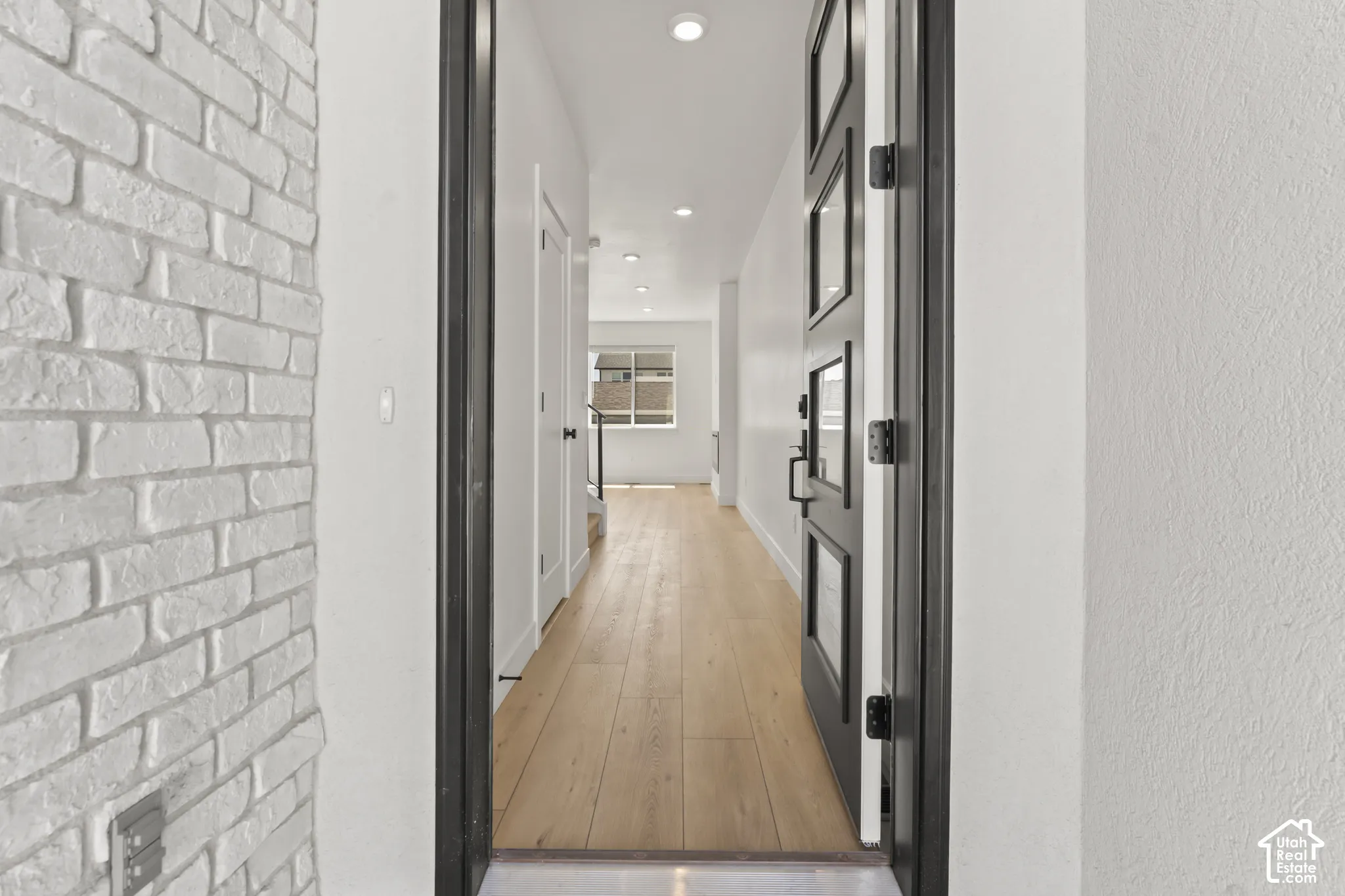 Entryway featuring a painted brick accent wall, wood-finish flooring, and a multi-panel door with glass inserts